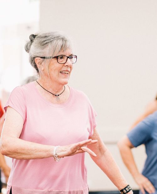 A woman taking part in a standing exercise class.
