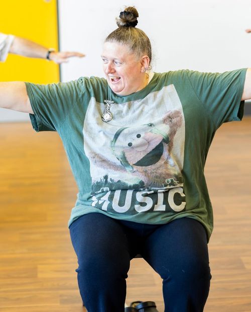 A woman holding both arms out to the side during a class.